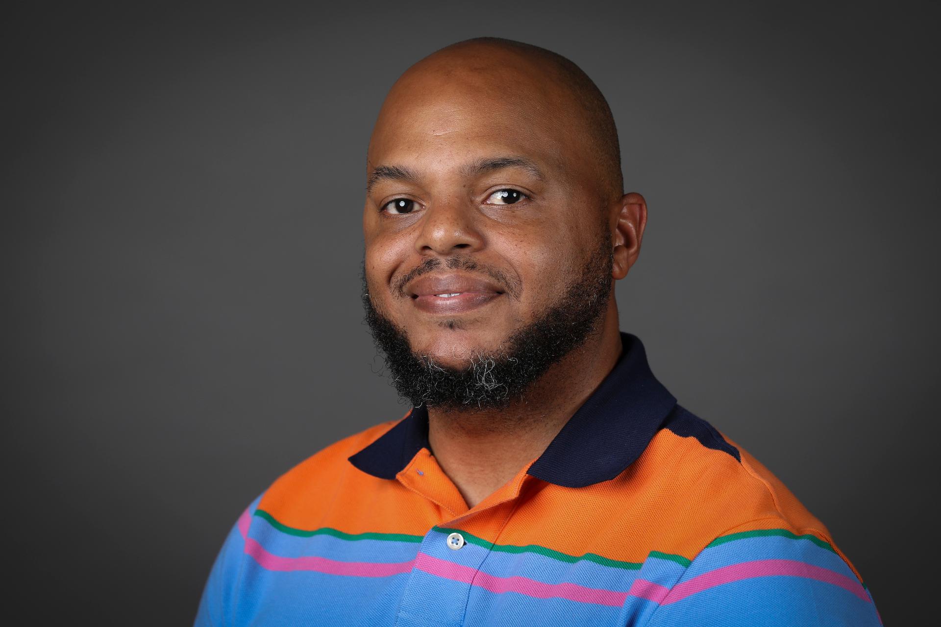 Man in polo in front of grey background.